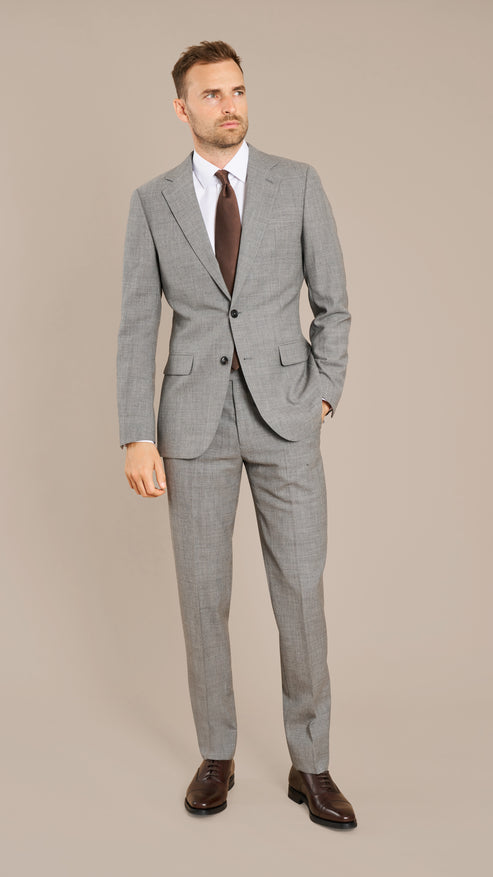 Man wearing a gray checkered suit with a brown tie on a beige background