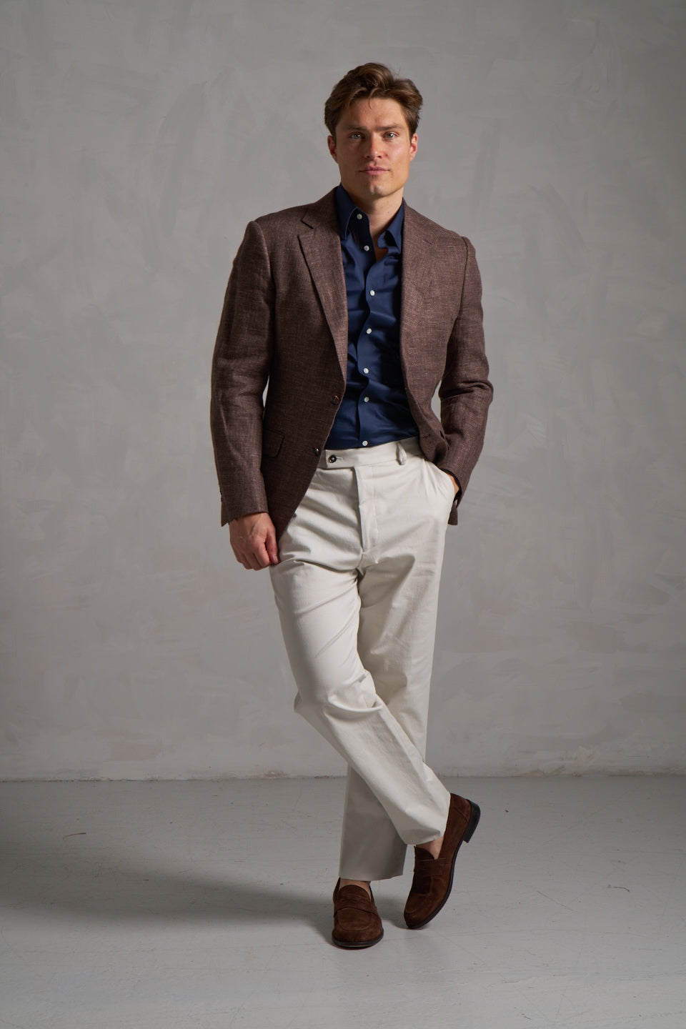 Brown linen jacket with a navy shirt and cream trousers