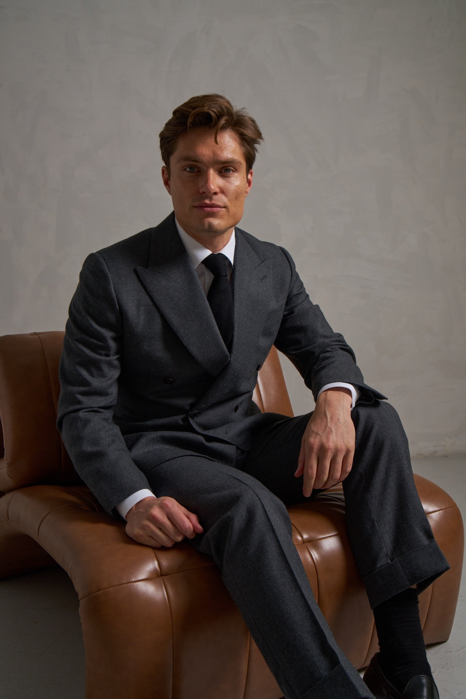 Charcoal double-breasted flannel suit, seated