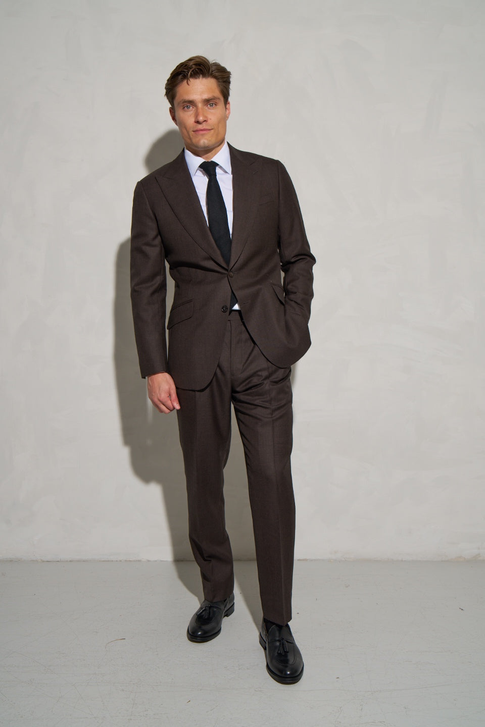 Brown made-to-measure suit with a black tie