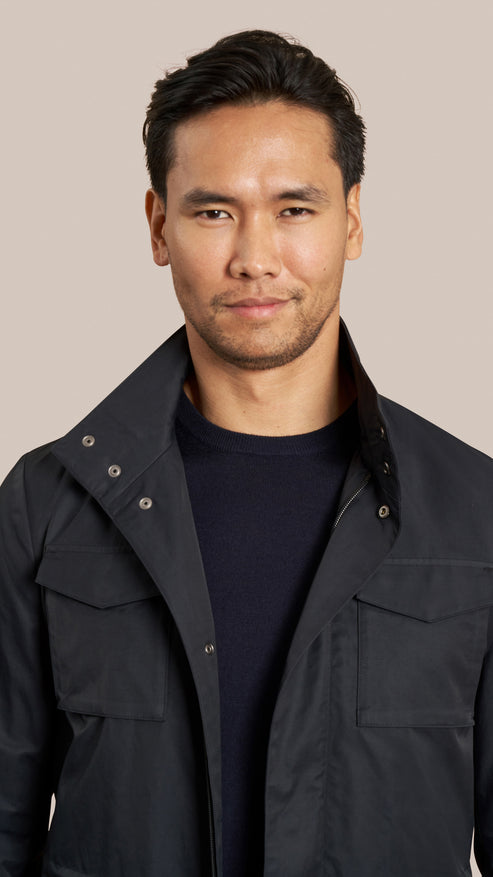 Man wearing a dark jacket against a beige background