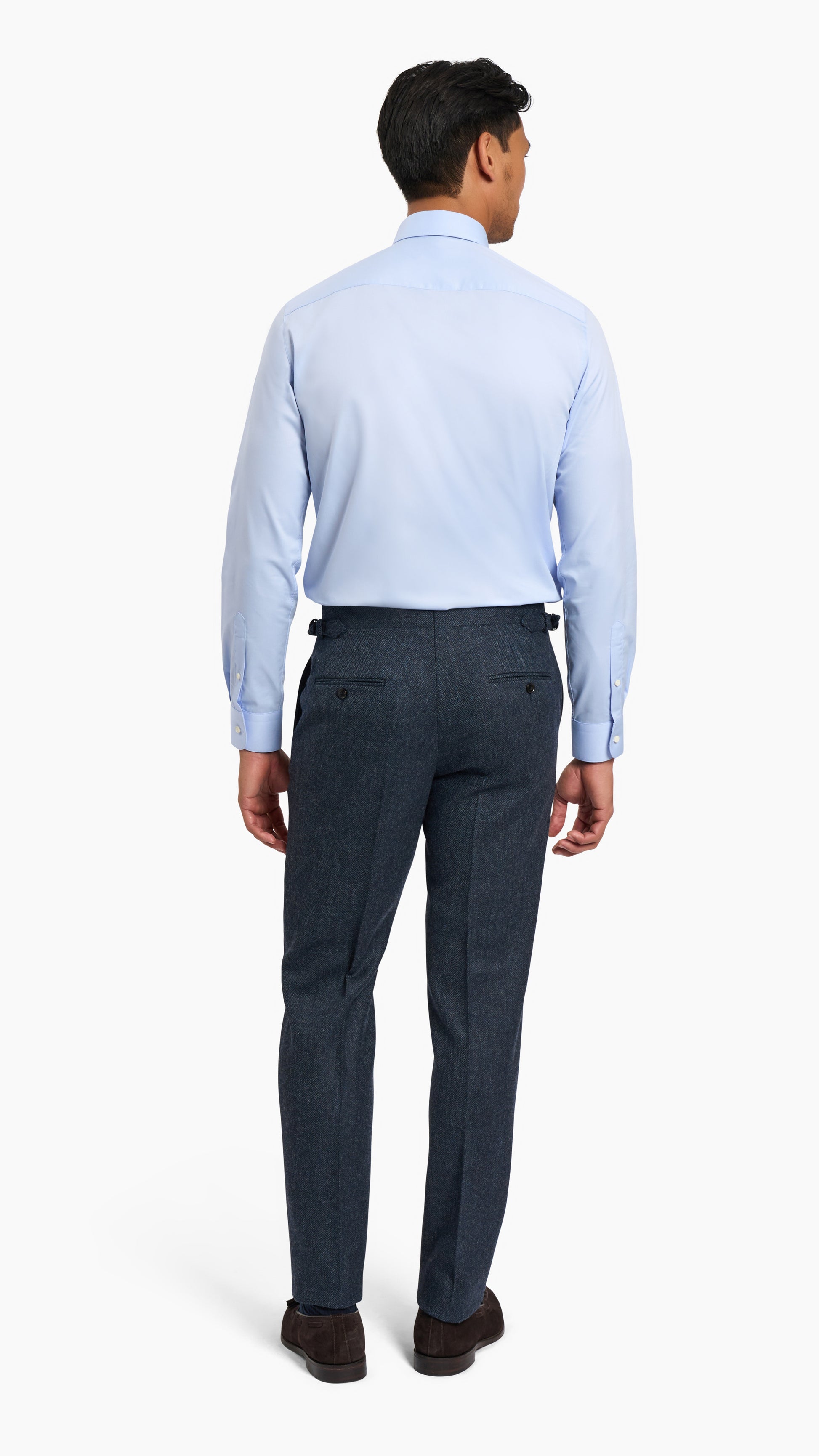 Man wearing Abraham Moon Navy Tweed Suit trousers with light blue dress shirt and dark shoes, back view.