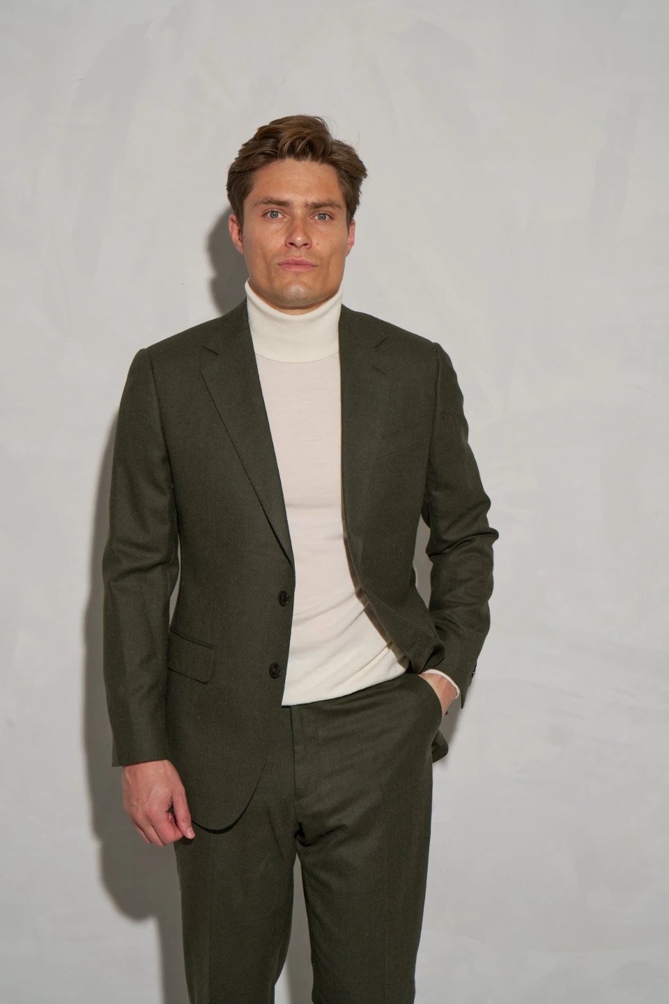 Olive made-to-measure suit with cream roll-neck